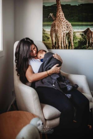 Newborn Photograph - a mother sits in a nursery cuddling her baby