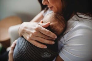 Newborn Photograph - a mother snuggles her baby boy on her chest