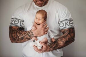 Newborn Photograph - a fathers big arms hold his tiny baby boy