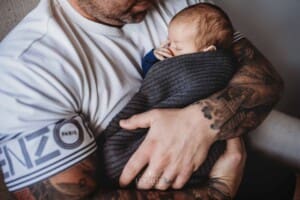Newborn Photograph - a father cuddles his sleeping baby boy