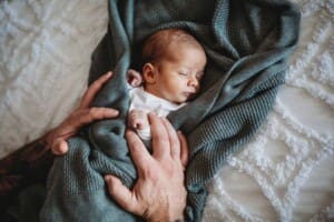 Newborn Photograph - a fathers big hands hold his tiny baby boy