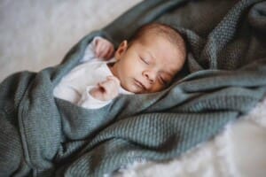Newborn Photograph - a newborn sleeping wrapped in a blanket