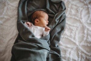 Newborn Photograph - a baby sleeps wrapped in a blanket