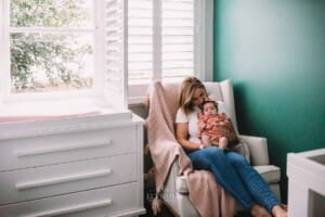 Newborn Photography - a mother sits holding her baby girl in the nursery