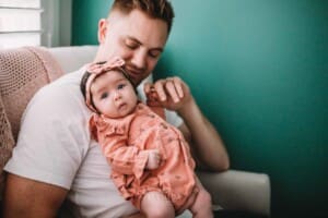 Newborn Photography - a dad holds his baby girl in his lap