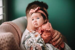 Newborn Photography - a father holds his baby girl over his shoulder
