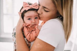Newborn Photography - a mother kisses her baby girl on the cheek
