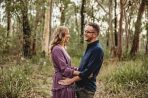 Engagement Photography - A couple stand cuddling in bushland