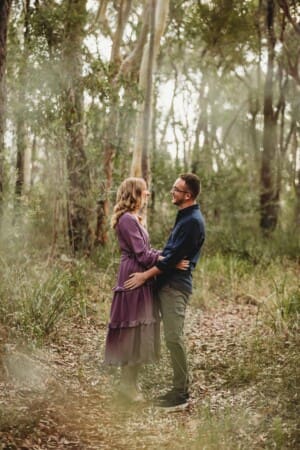 Engagement Photography - a couple laugh together standing in bushland