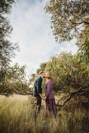 Engagement Photography - a couple share a kiss as they stand in long grass