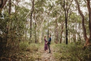Engagement Photography - a couple stand amongst tall trees and cuddle