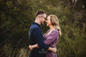 Engagement Photography - a couple rest their foreheads together as they stand in long grass