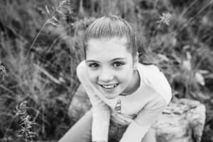 A girl sitting in a long field of grass