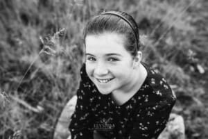 A girl sitting in a long field of grass