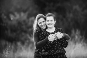 A mother cuddles her daughter around the shoulders