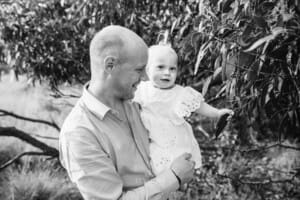 A father holds his little girl as she plays with leaves