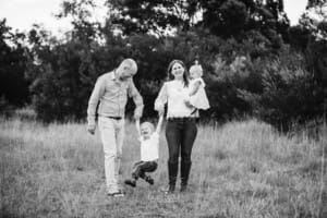 A family walk through a grassy field with their children