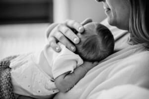 A mothers hands hold her newborns tiny head