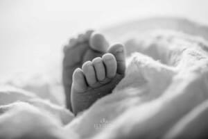 Newborn baby toes poke out from a white wrap