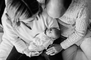Parents sit on a bed holding their newborn baby girl