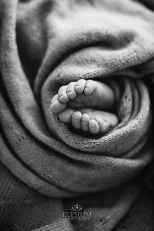 Newborn baby details, tiny toes sticking out of a wrap
