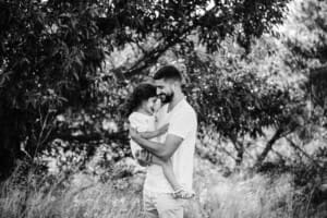 A father hugs his little girl as they stand in long grass