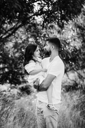 A father hugs his little girl as they stand in long grass
