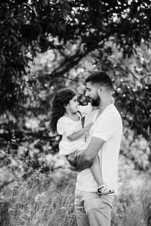 A father hugs his little girl as they stand in long grass