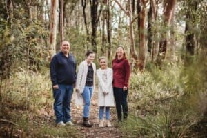 A family stand on a dirt path in the bush
