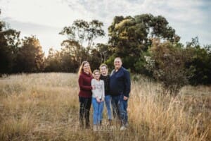 A family cuddle in a grass field at sunset