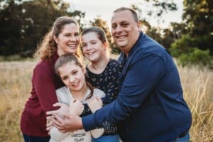 A family cuddle together standing in long grass
