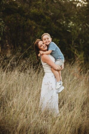 A mother hugs her son as they stand in long grass