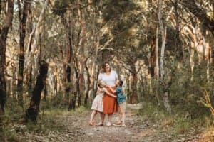 A mother hugs her children standing on a bush path