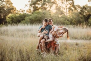 A mother sits her children in her lap and tickles them