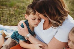 A little boy sits and cuddles his mother