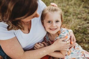 A little girl sits and cuddles her mother