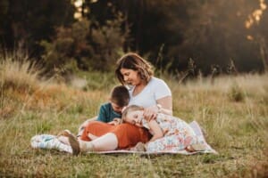 A mother sits cuddling her children at sunset