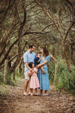 Children stand with their parents on a sandy beach path