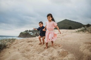 Children hold hands as they run down sand dunes