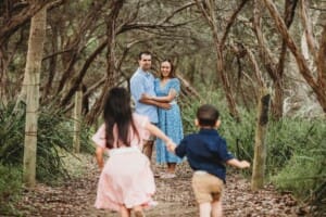 Children race along a sandy beach path towards their parents