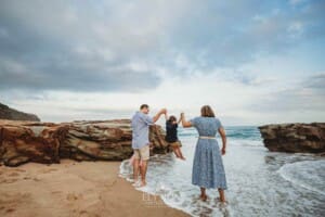 Parents swing their little boy between them at the beach