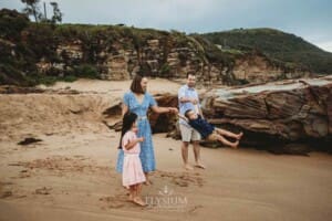 Parents swing their little boy between them at the beach