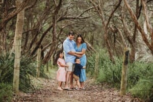 Children stand with their parents on a sandy beach path