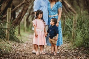 Children stand with their parents on a sandy beach path