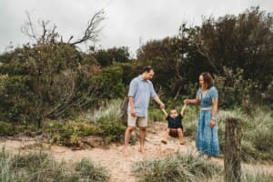 Parents swing their little boy between them at the beach