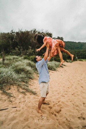A dad lifts his daughter above him at the beach