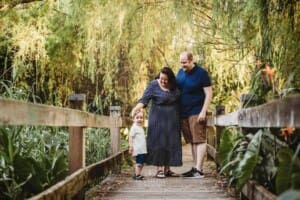 A couple stand with their son on a boardwalk
