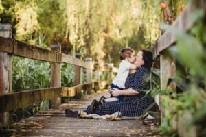 A little boy kisses his mum as they sit on a boardwalk