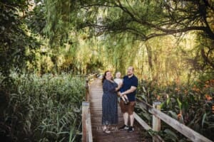 Parents cuddle their little boy standing on a boardwalk