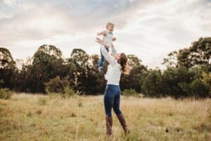 A mother tosses her giggling son in the air above her